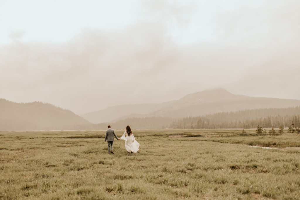 Bride and groom hold hands while walking through a field during their Oregon elopement photographed by Morgan Wirth Photography