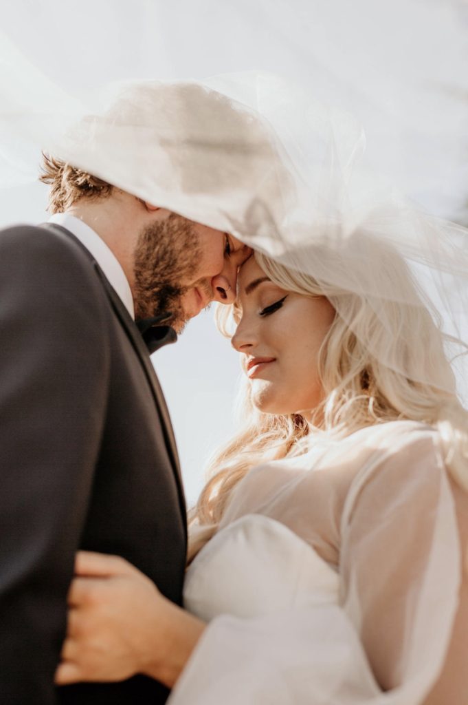 Choosing An Oregon Elopement Photographer: Everything You Need To Know. Bride and groom press their foreheads against each other's and close their eyes under her veil photographed by Morgan Wirth