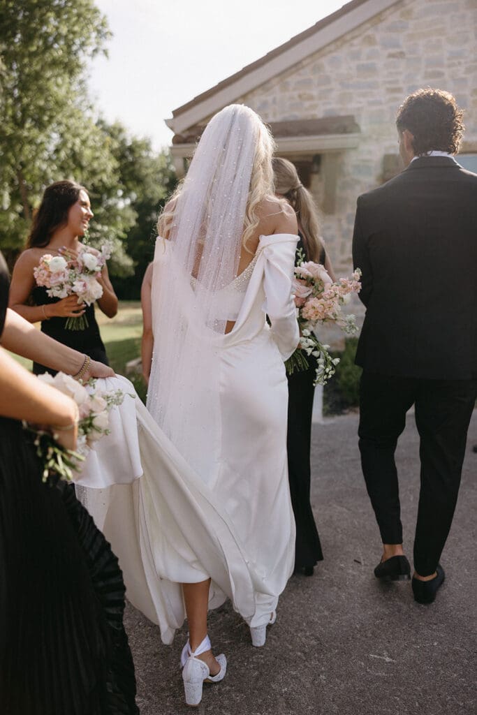 bridesmaid holding brides dress as she walks