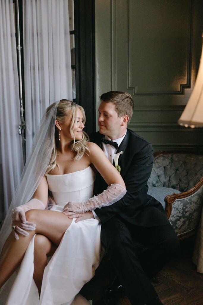 Bride and groom sitting closely on a vintage sofa, romantic editorial and documentary portrait at The Mason wedding venue in Dallas.