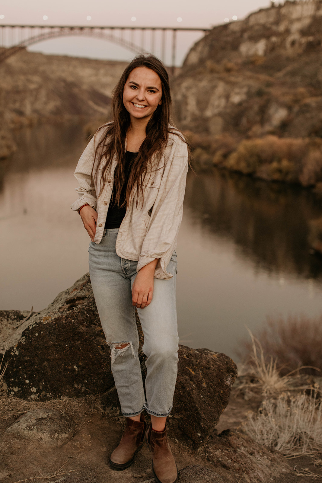 Morgan Wirth smiles while standing in front of a lake and bridge during a photography workshop.