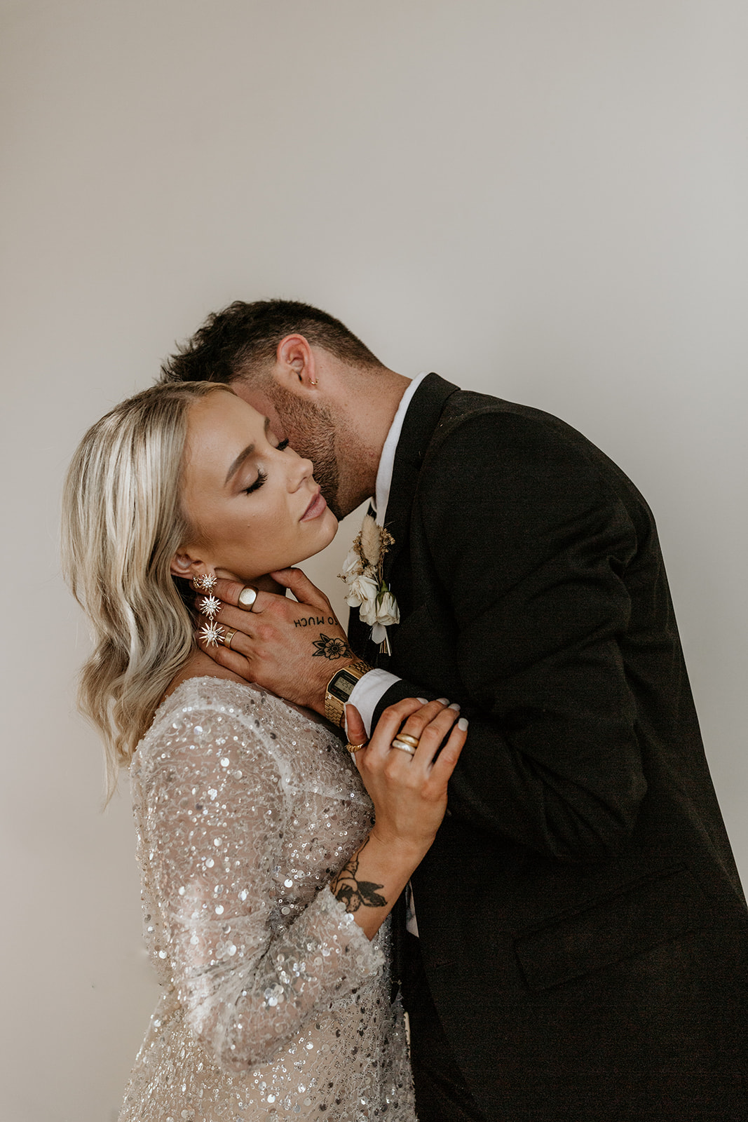 A groom leans in to kiss his bride on her neck during their modern and edgy styled wedding shoot at the Birdie by Morgan Wirth Photography.