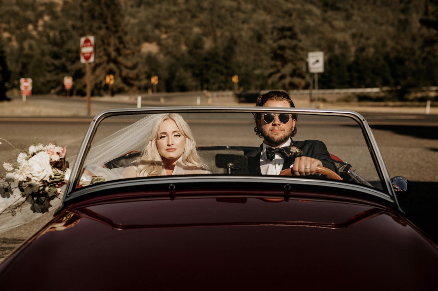 Bride and groom ride in a vintage sports car during their elopement in the Pacific Northwest