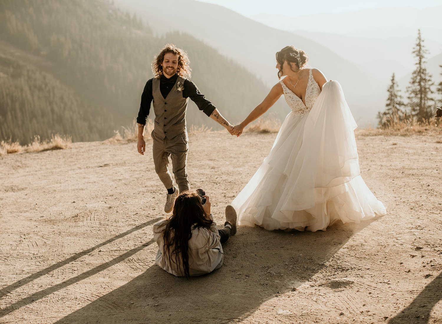 Bride and groom pose hand in hand as Oregon Wedding Photographer Morgan Wirth takes an upwards angle photo of them