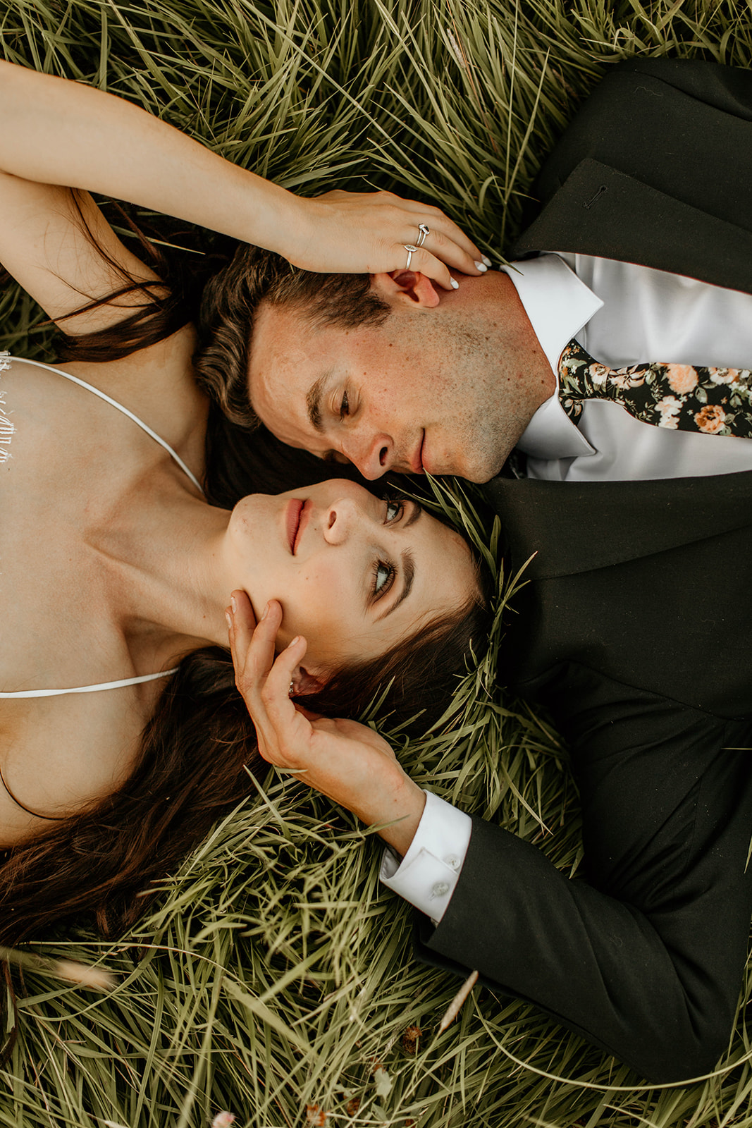 Bride and groom lay on the grass and look at each other adoringly, taken by Morgan Wirth Photography