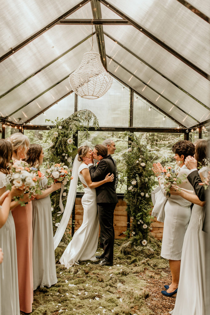 Newlywed couple share a kiss as they are pronounced husband and wife with their guests cheering on 