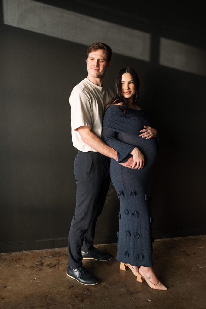 Close-up maternity detail of baby bump with natural sunlight in a Dallas studio.