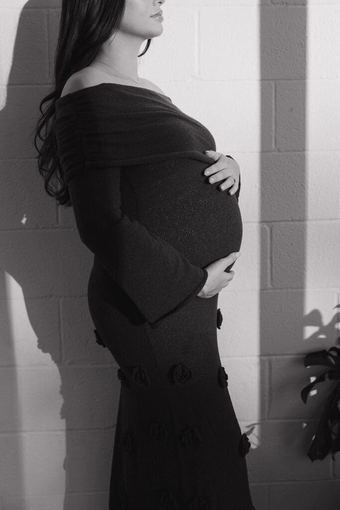 Editorial black and white maternity portrait with soft window light in a Dallas studio.