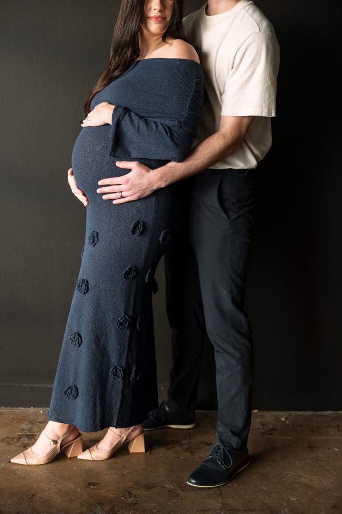 Intimate, documentary-style maternity portrait of an expecting mother in a navy dress at a Dallas studio.