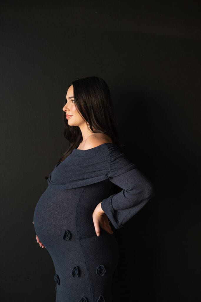 Side profile of expecting mother in elegant navy dress during an editorial Dallas maternity shoot.