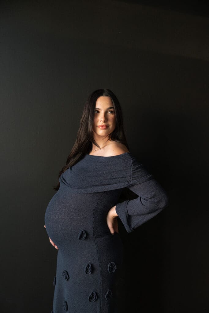 Side profile of expecting mother in elegant navy dress during an editorial Dallas maternity shoot.